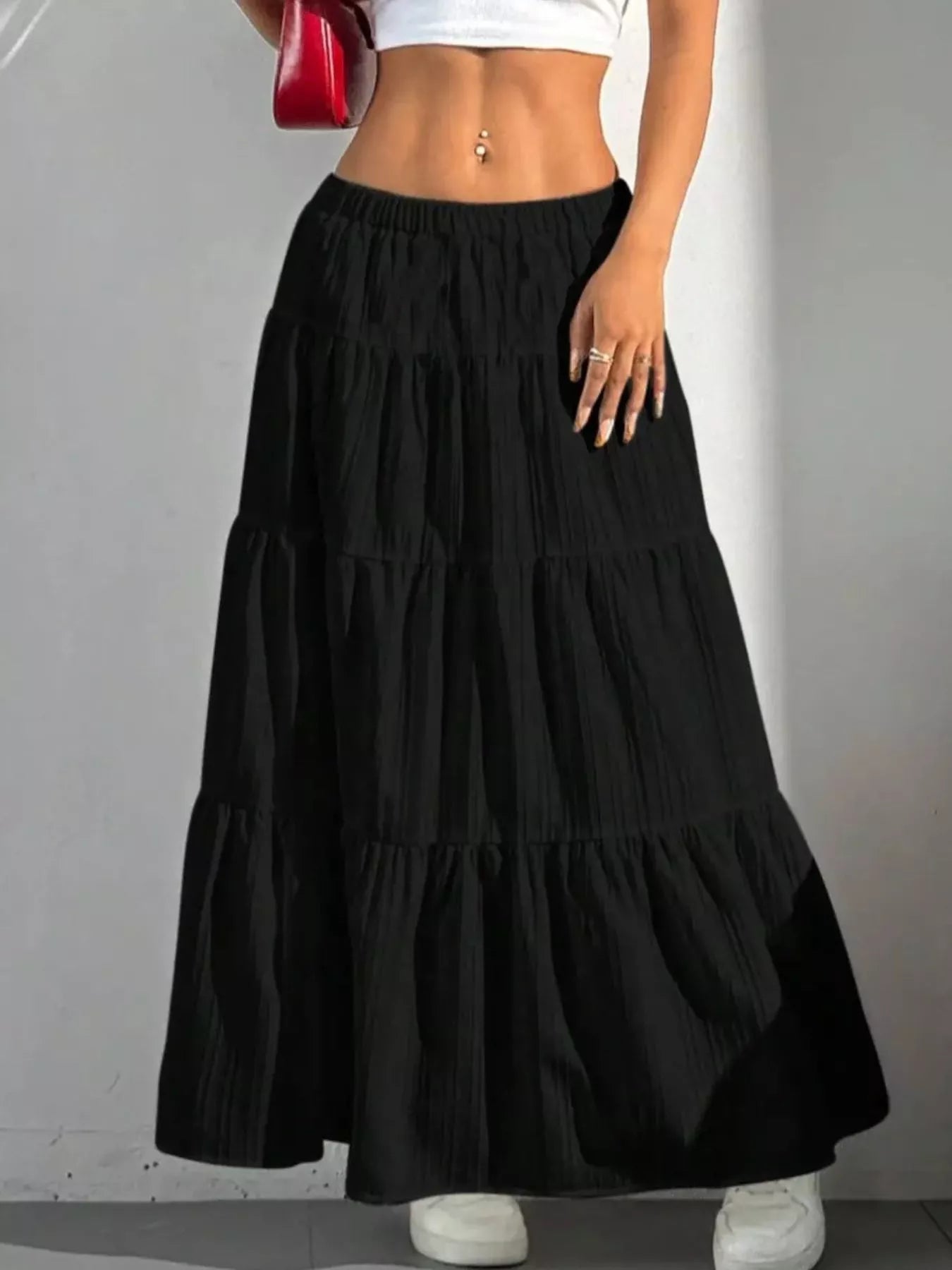 Black tiered skirt worn by a person on a plain background
