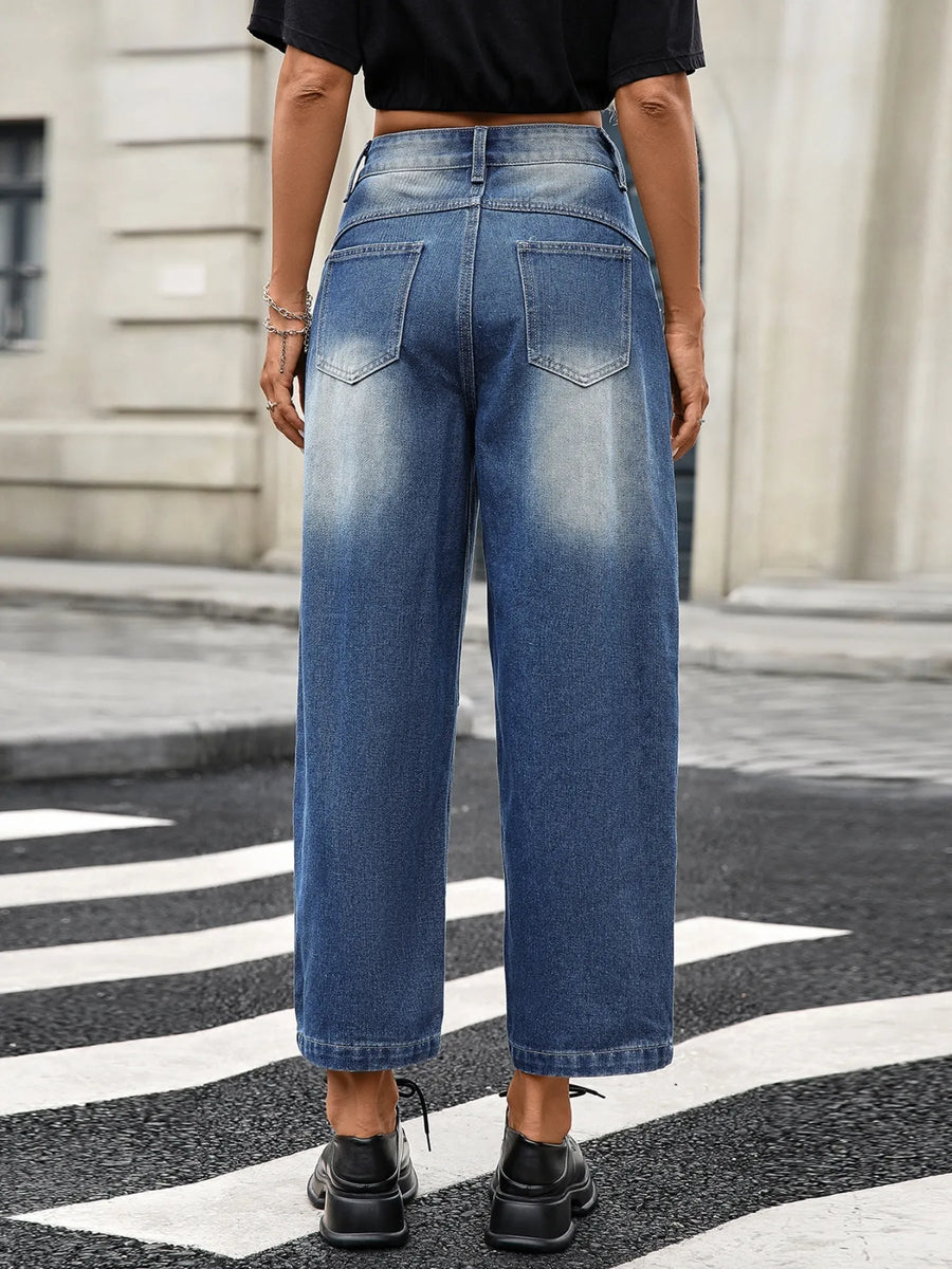 Person wearing blue jeans standing on a street with a blurred background