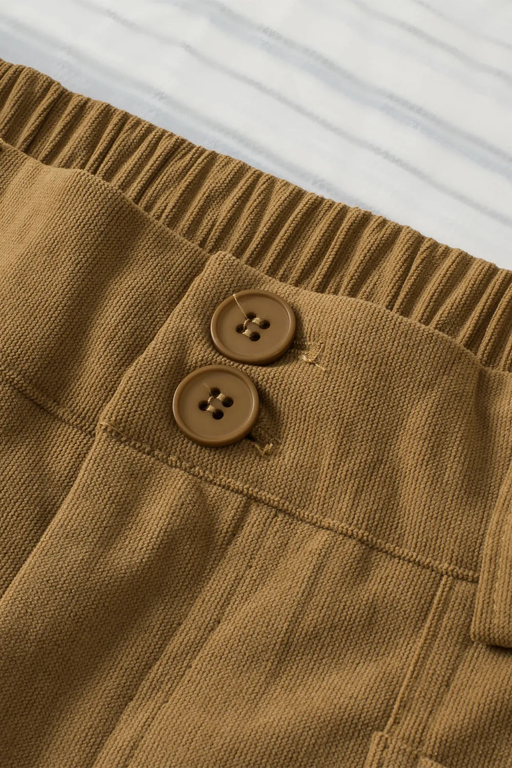 Close-up of brown corduroy pants with two buttons on a white background