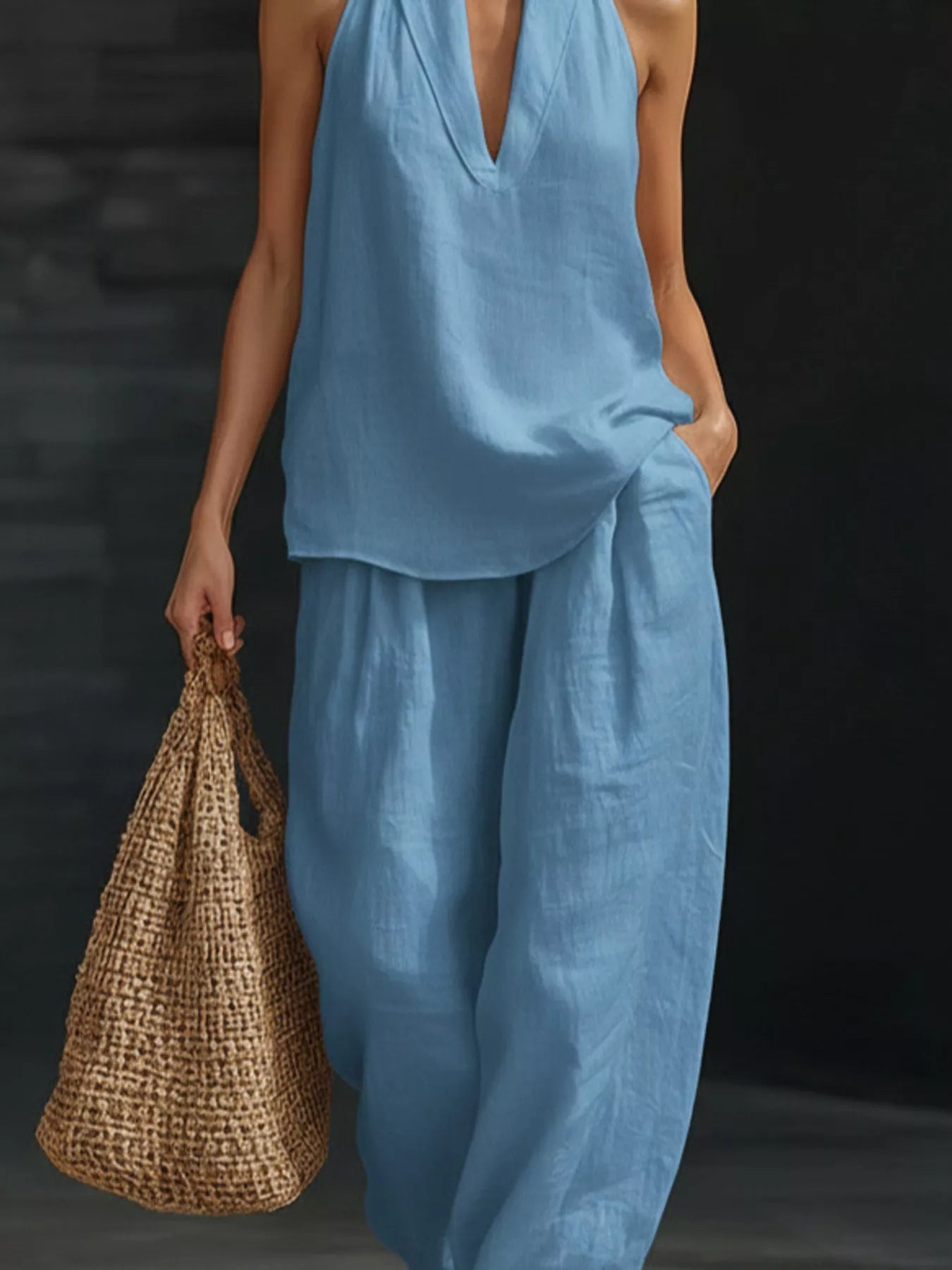 Person wearing a blue outfit holding a woven bag against a dark background