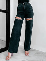 Black jeans with unique patchwork design worn by a person indoors.