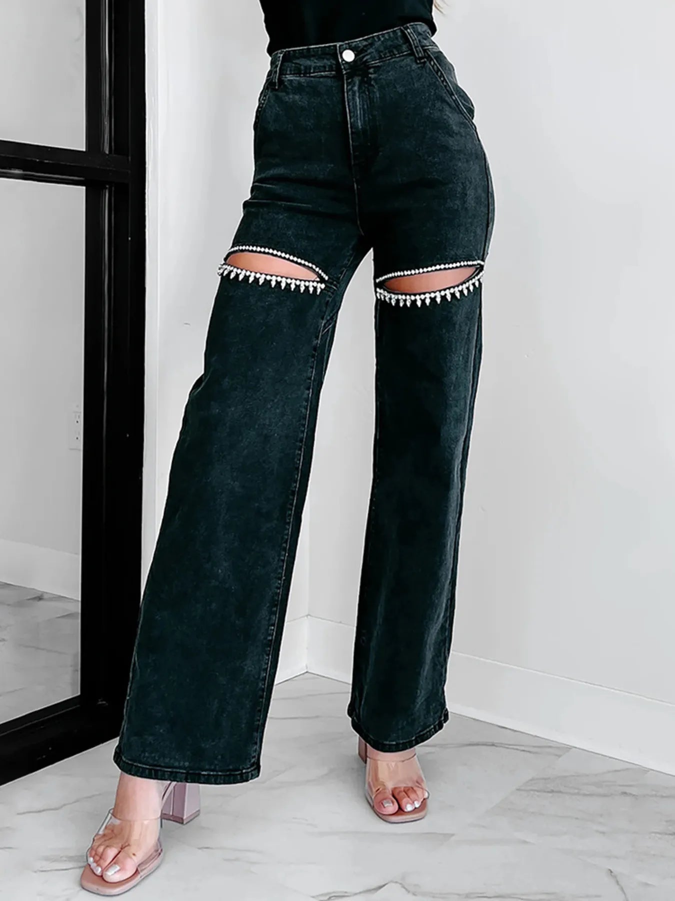 Black jeans with unique patchwork design worn by a person indoors.
