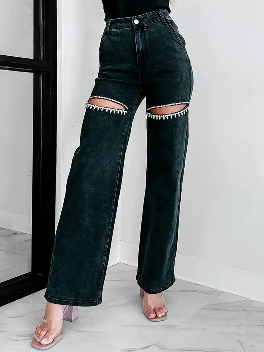 Black jeans with unique patchwork design worn by a person indoors.