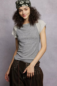 Woman wearing a gray t-shirt and dark pants with a headband against a gray background