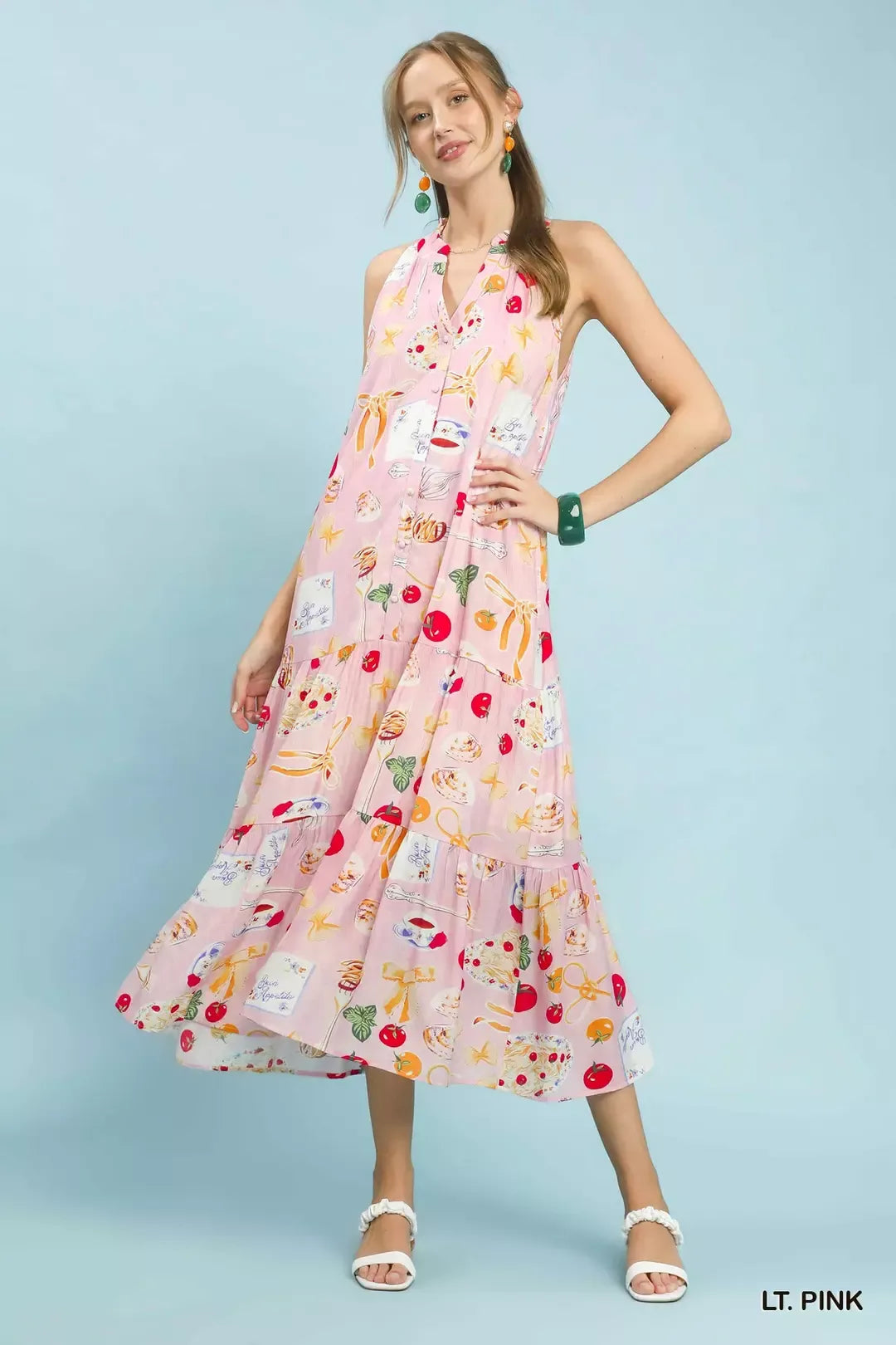 Woman wearing a light pink dress with colorful pattern on a light blue background