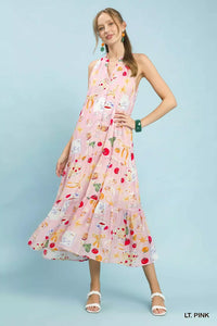 Woman wearing a light pink dress with colorful pattern on a light blue background