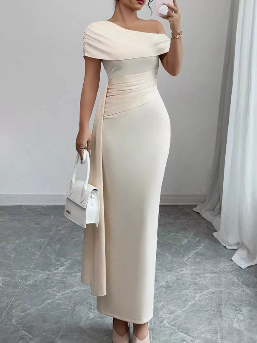 Woman wearing a beige off-shoulder dress holding a white handbag indoors.