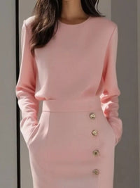 Pink outfit with gold buttons on a neutral background