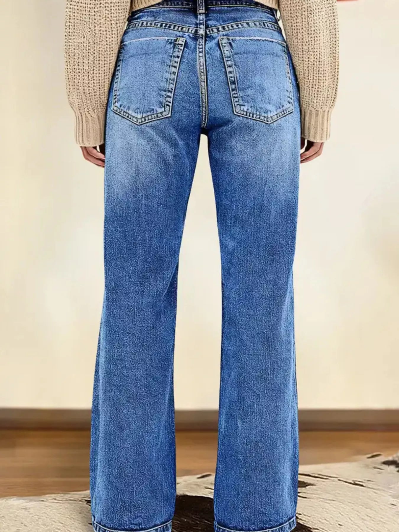 Person wearing blue flared jeans with a neutral background
