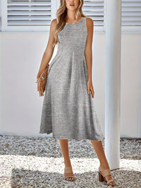 Woman wearing a gray sleeveless dress standing outdoors.