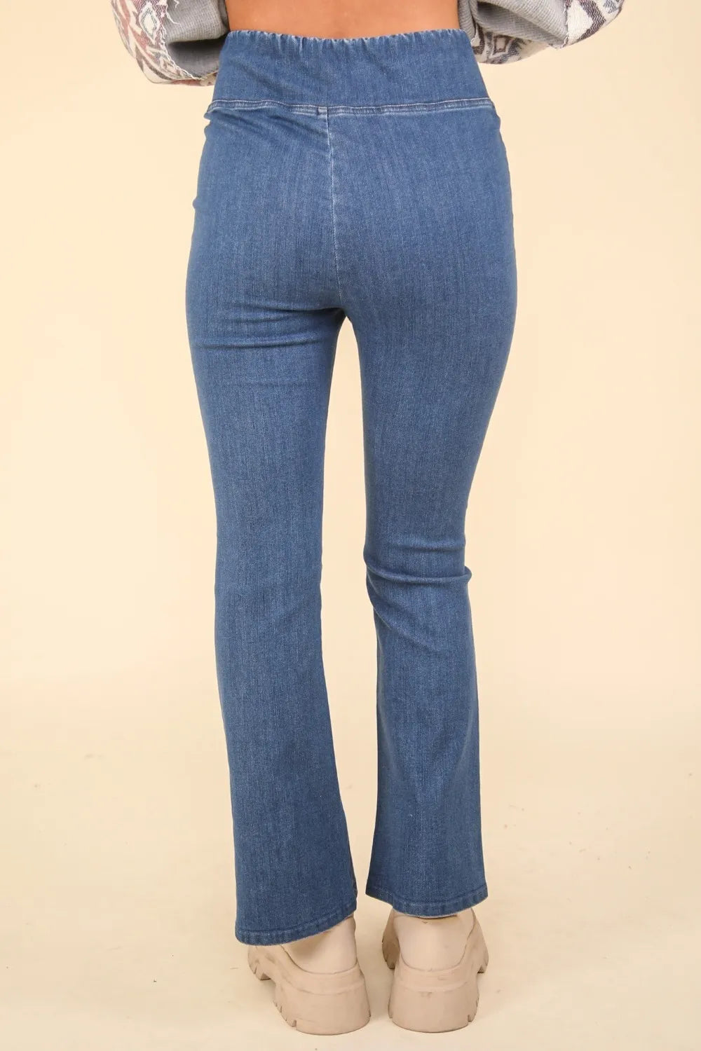 Blue jeans worn by a person on a beige background