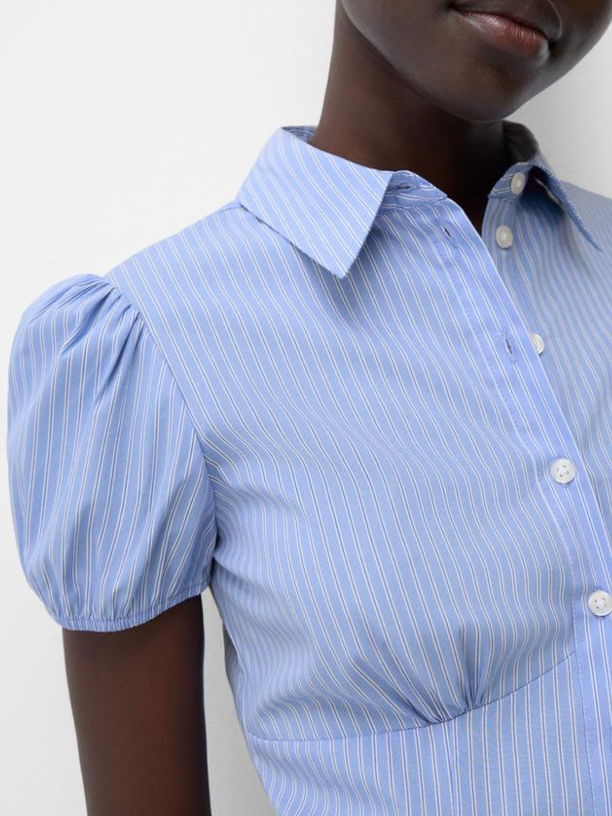 Blue striped shirt with puff sleeves worn by a person on a white background