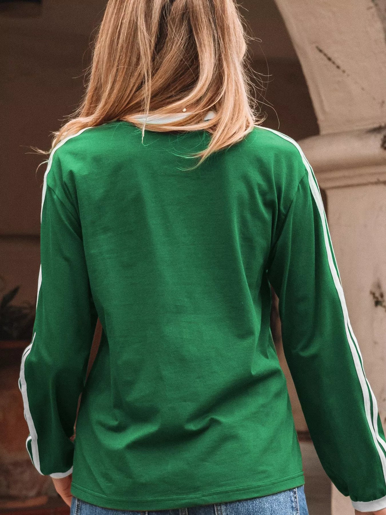 Green long-sleeve shirt with white stripes on the sleeves worn by a person.