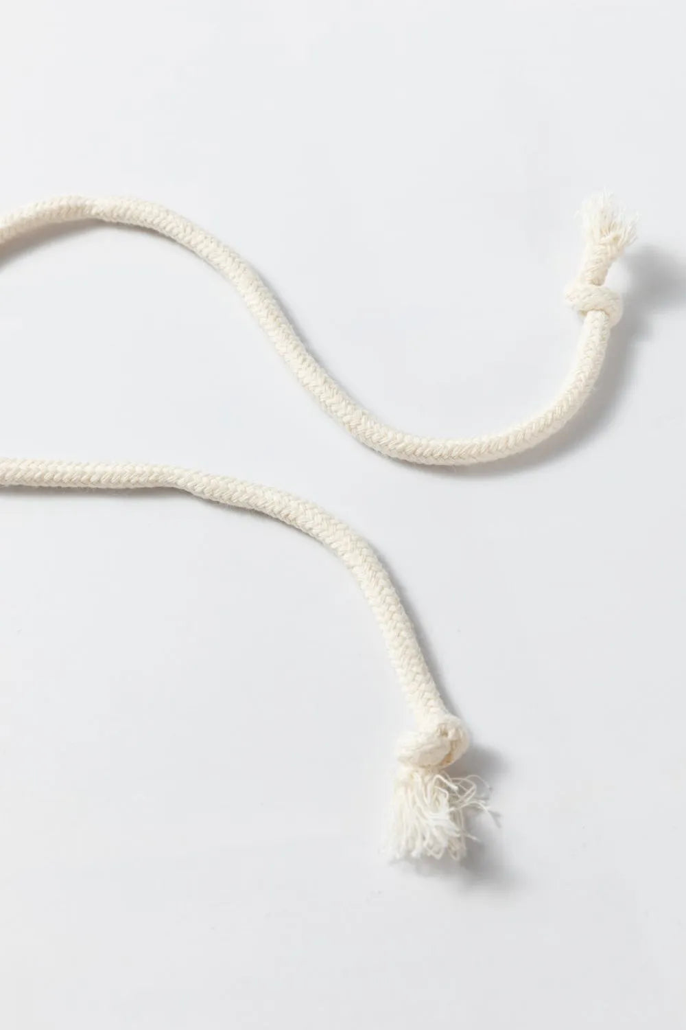 White cord with a tassel on a light gray background