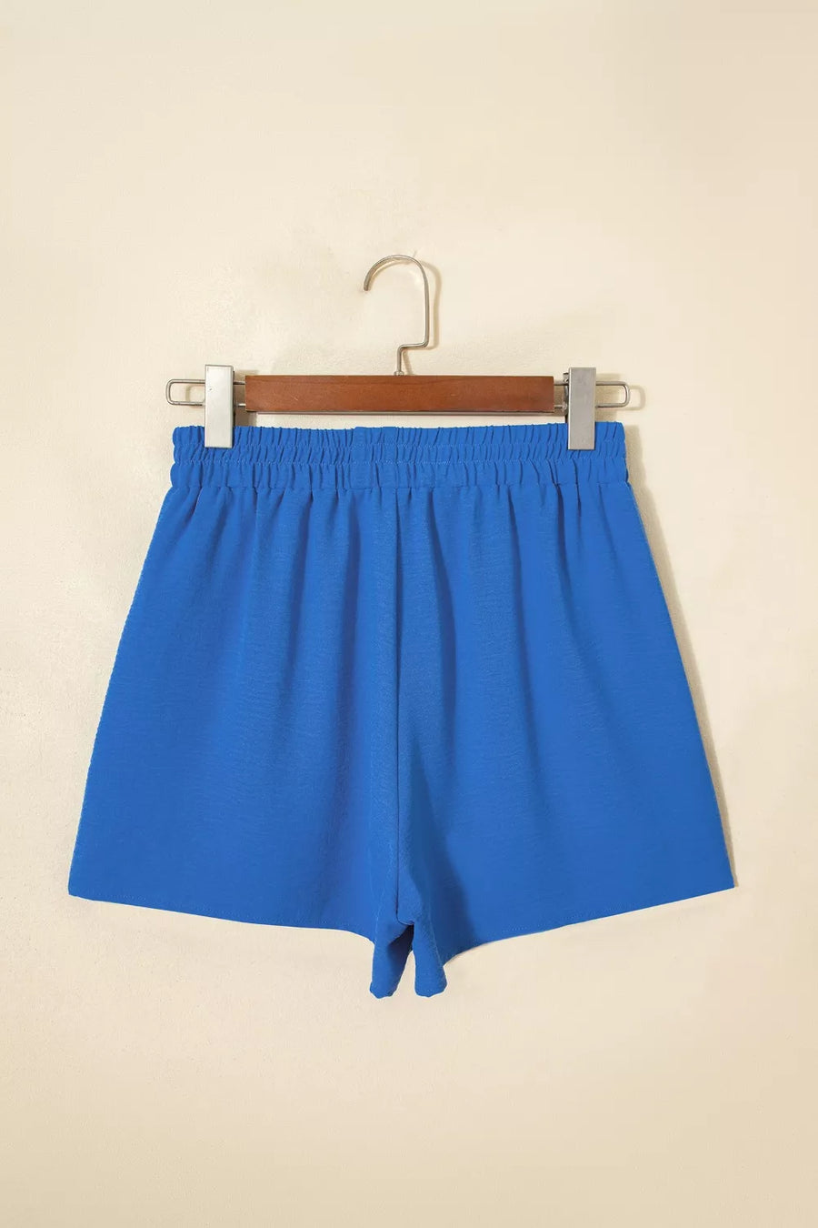 Blue shorts on a hanger against a beige background