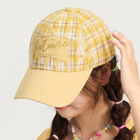 Person wearing a yellow plaid cap with 'Future' embroidered on it against a plain background