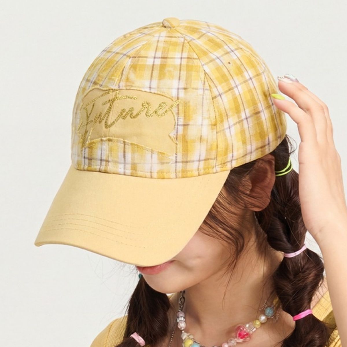 Person wearing a yellow plaid cap with 'Future' embroidered on it against a plain background