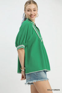 Woman wearing a green textured top with white trim on a white background