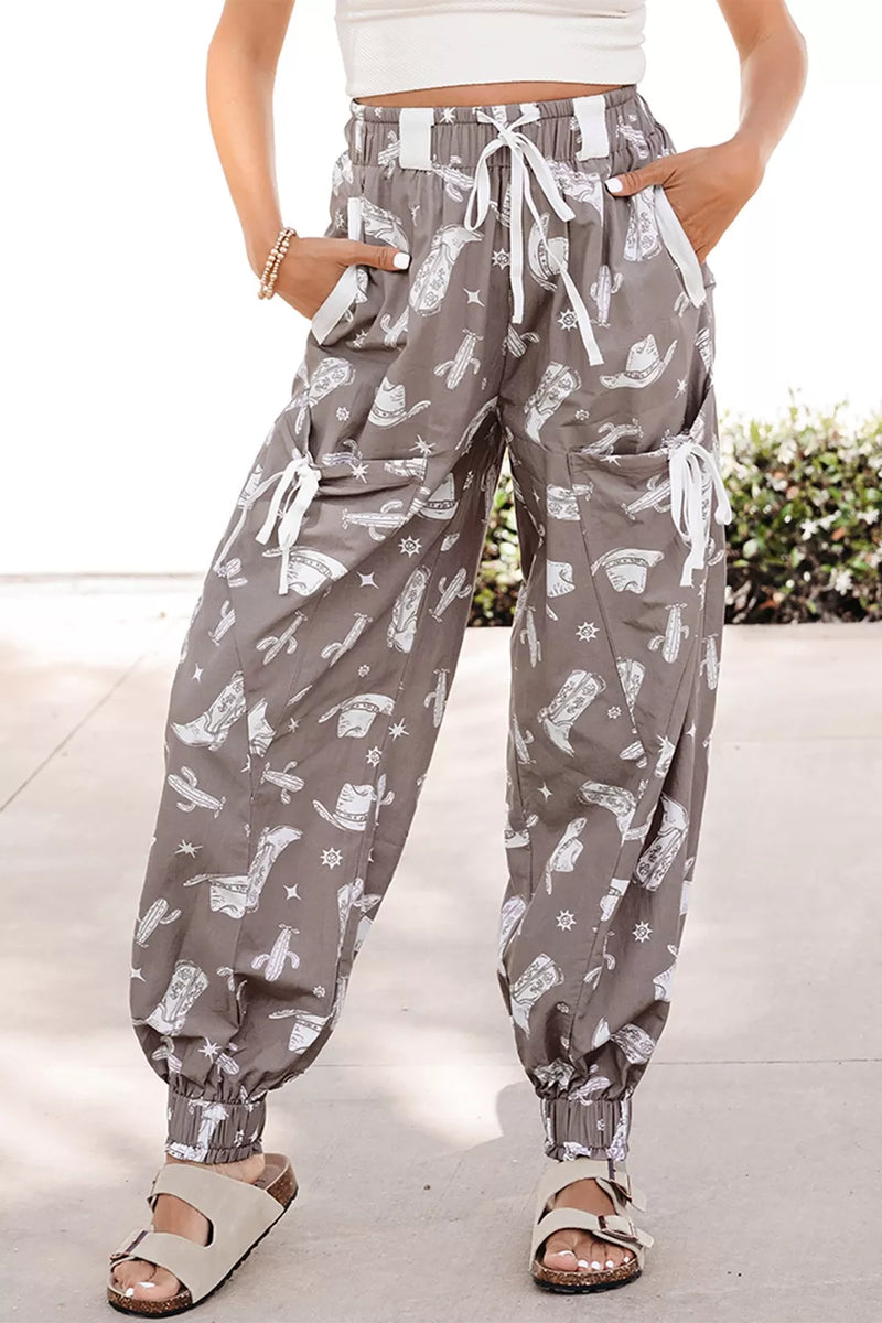 Person wearing gray patterned pants with a white top and sandals on a light background