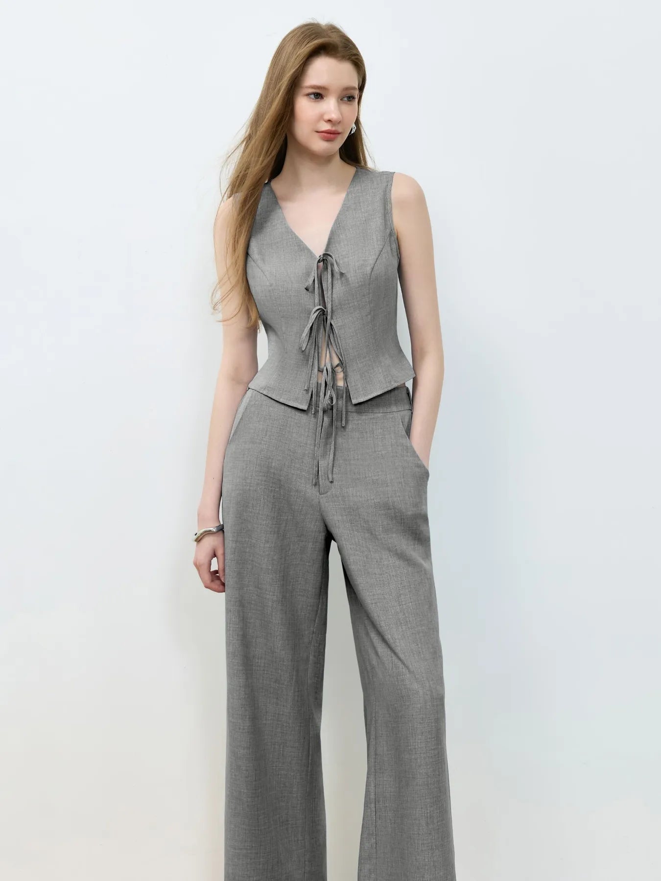 Woman wearing a gray sleeveless top and wide-leg pants on a white background
