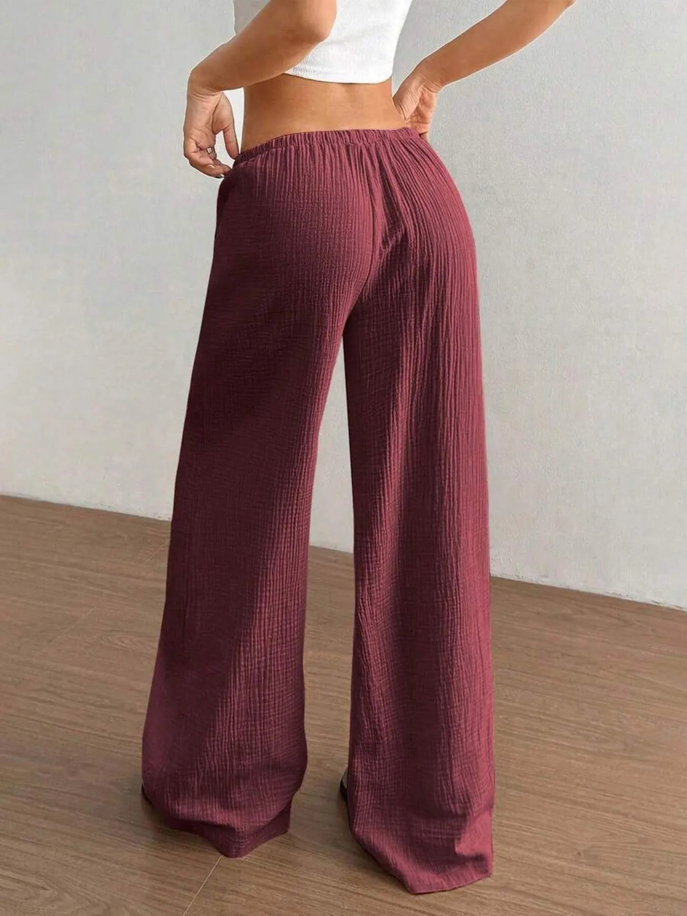 Maroon ribbed wide-leg pants worn by a person on a wooden floor.