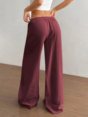 Maroon ribbed wide-leg pants worn by a person on a wooden floor.