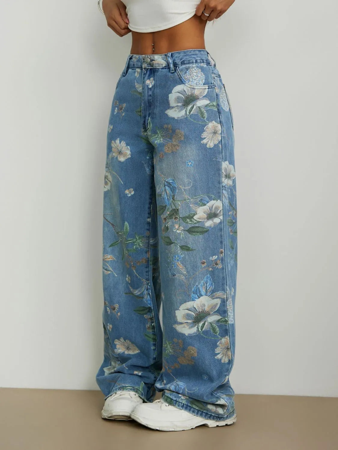 Blue floral jeans worn by a person on a plain background