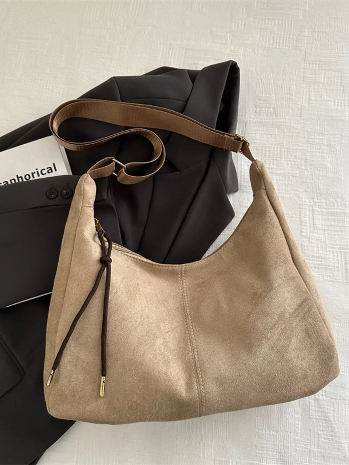 Beige handbag with brown strap on a light background