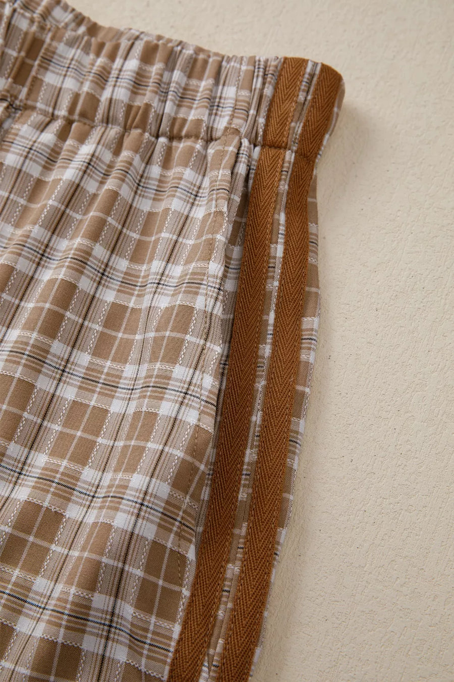 Brown plaid shorts with a brown waistband on a beige background