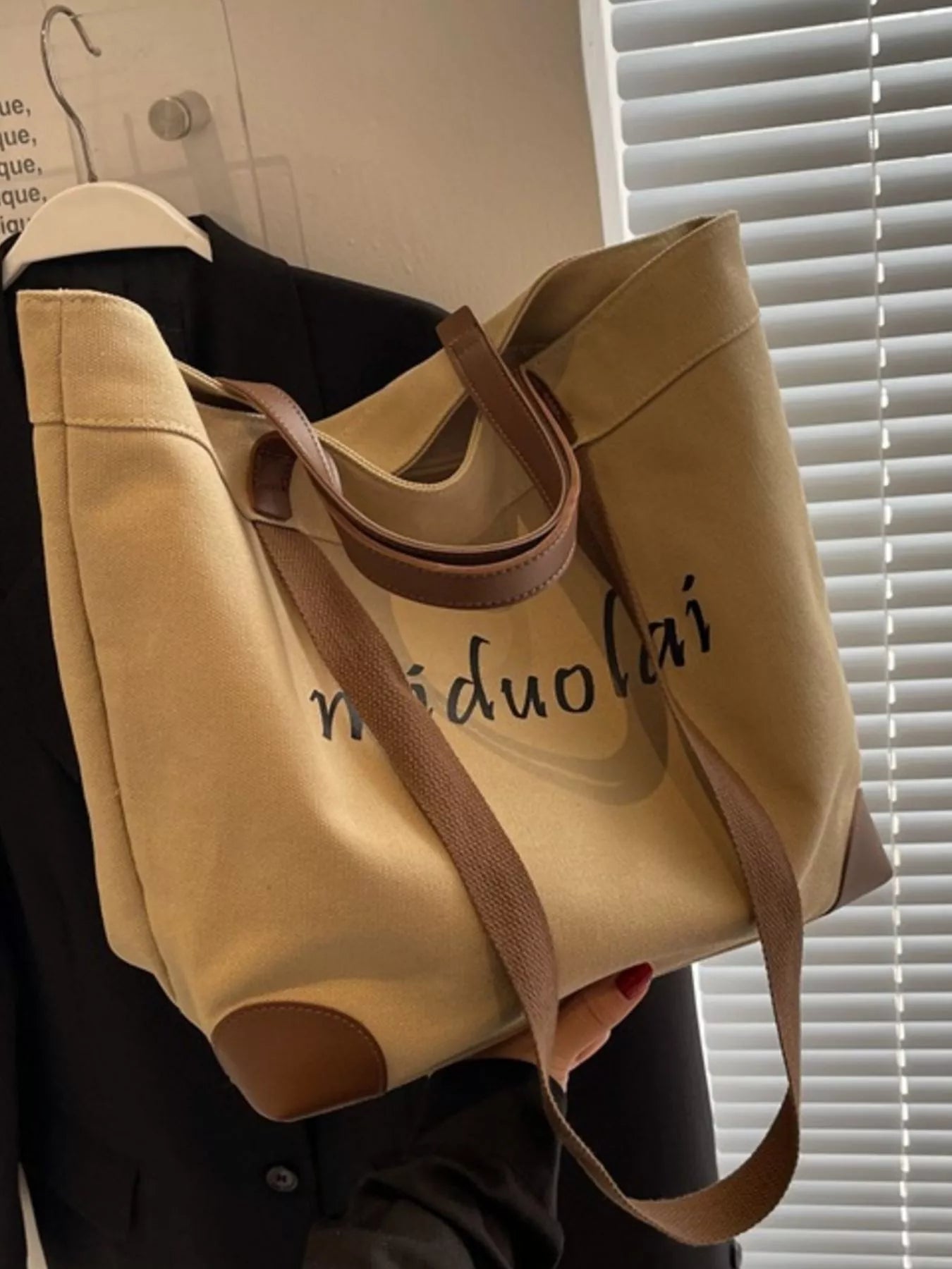 Beige tote bag with brown handles and trim, featuring the brand name 'midooolai', held against a neutral background.