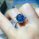 Blue gemstone ring on a finger with a blurred background