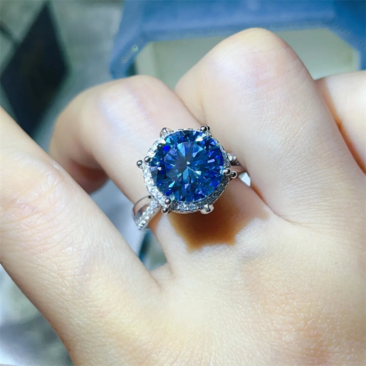 Blue gemstone ring on a finger with a blurred background
