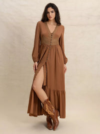 Woman wearing a long brown dress with a slit and matching boots on a beige background