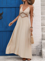Woman wearing a beige maxi dress with a blue door and white wall in the background