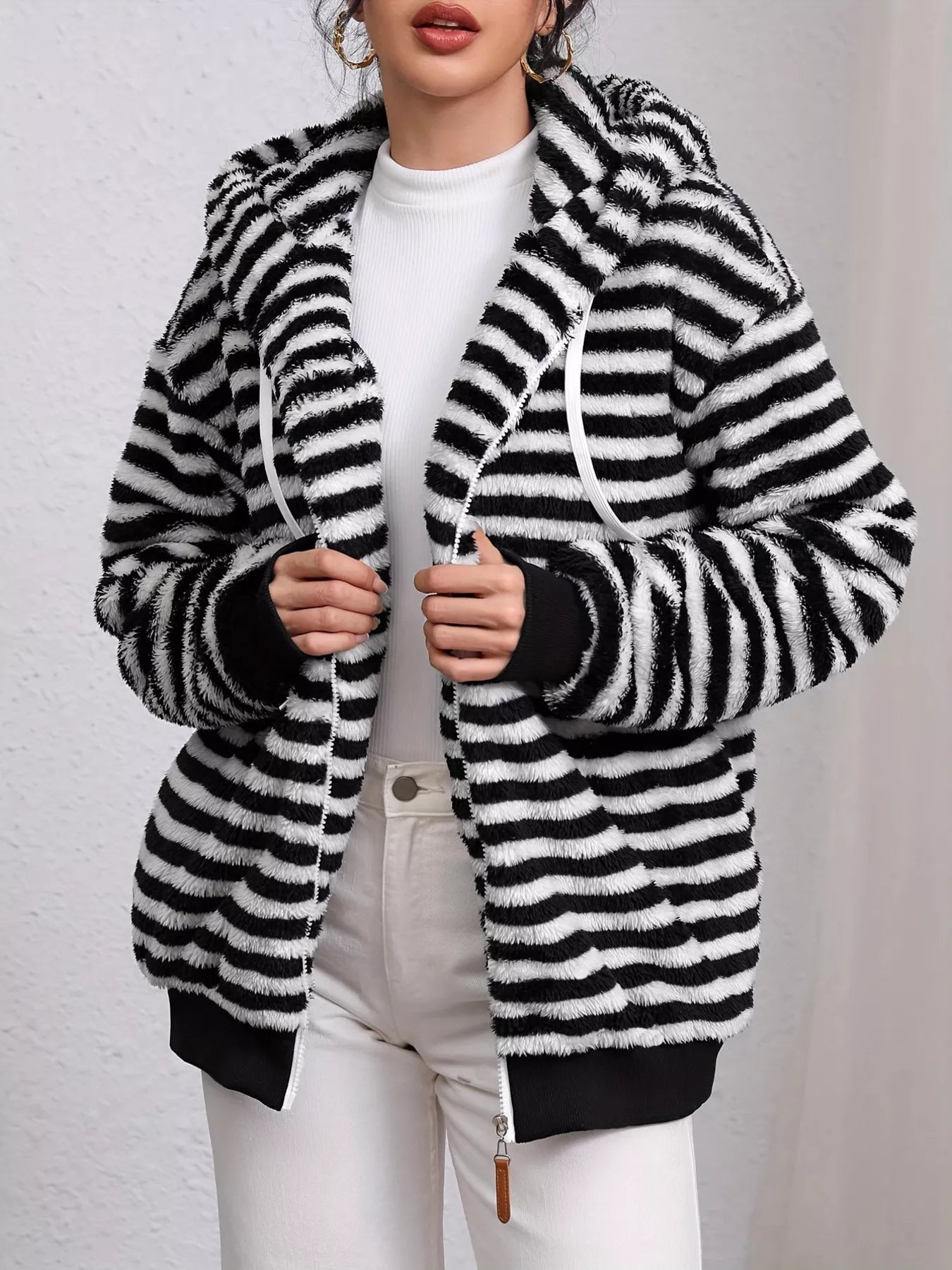 Person wearing a black and white striped coat against a plain background