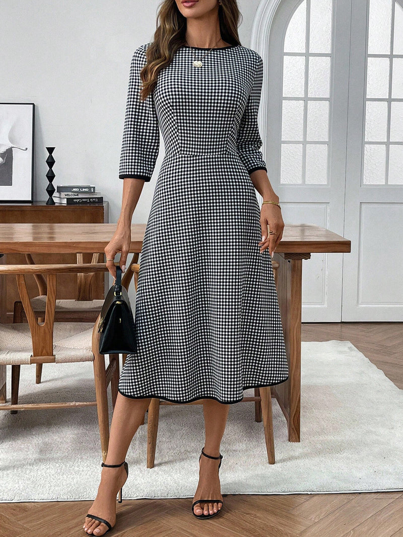 Woman in a black and white checkered dress standing in a room with wooden furniture.