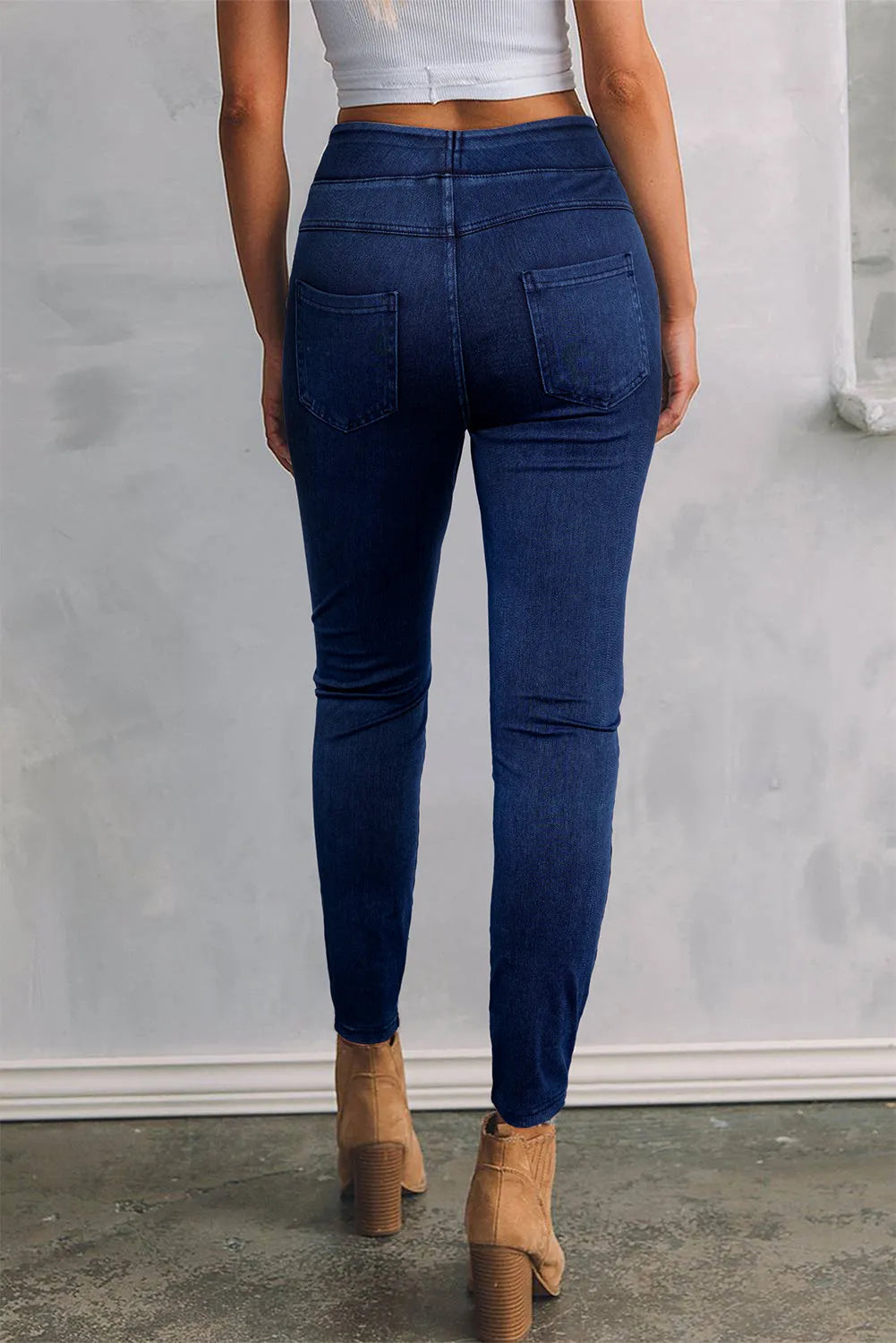 Person wearing blue jeans and tan boots against a plain background