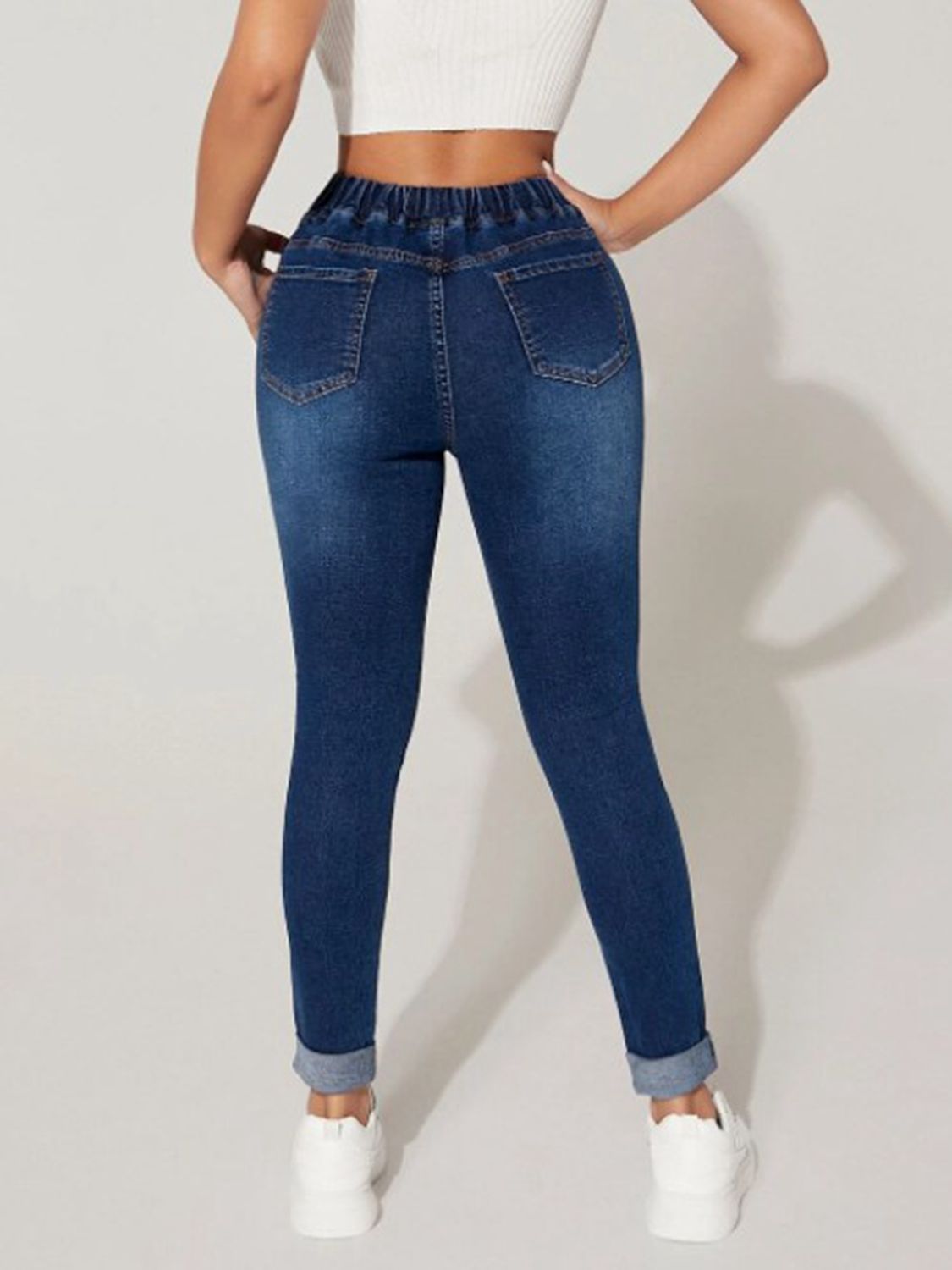 Person wearing blue jeans on a plain background