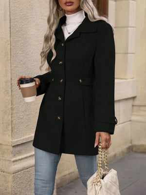 Person wearing a black coat holding a coffee cup and a handbag on a city street.