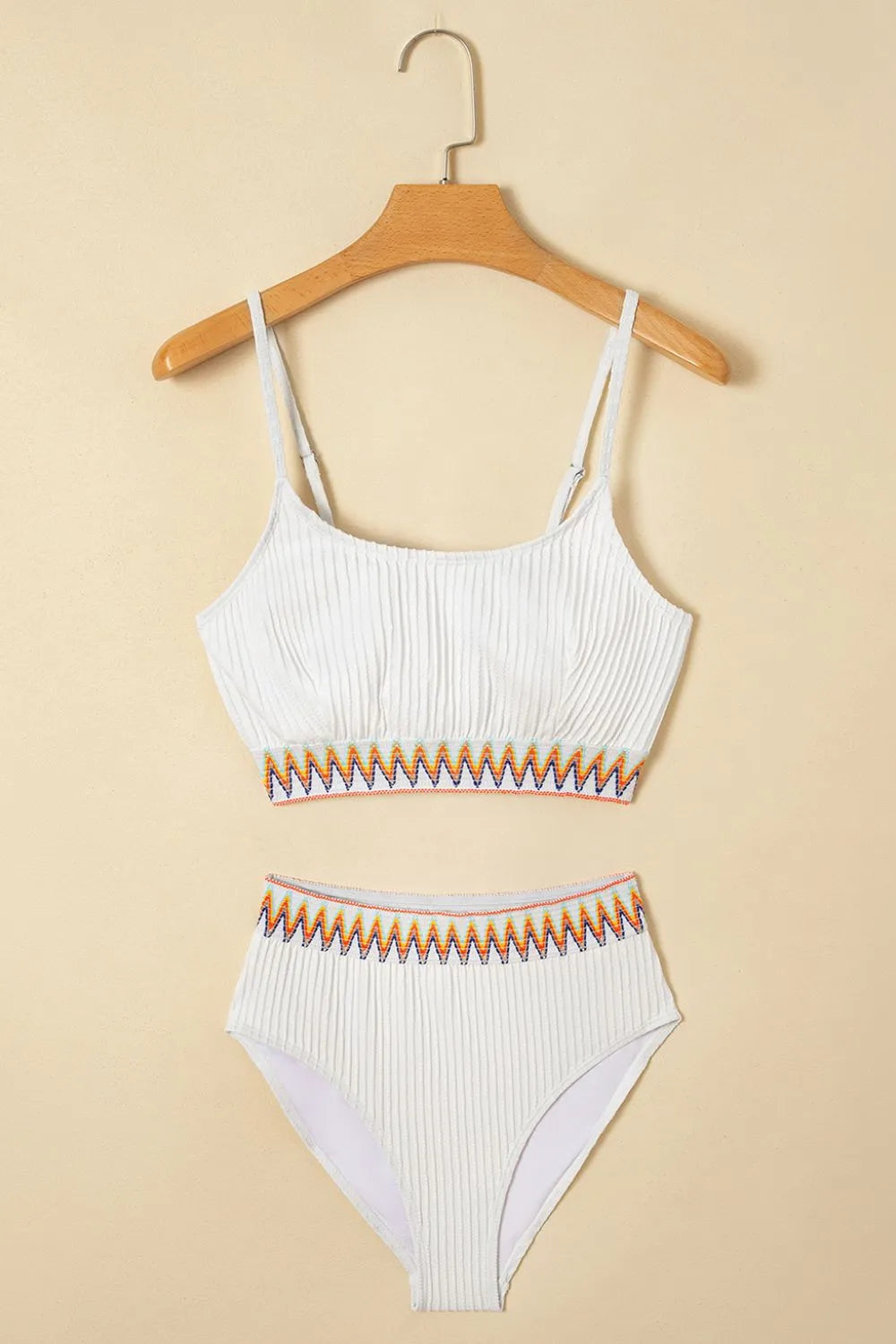 White ribbed bikini set with orange and yellow pattern on a beige background