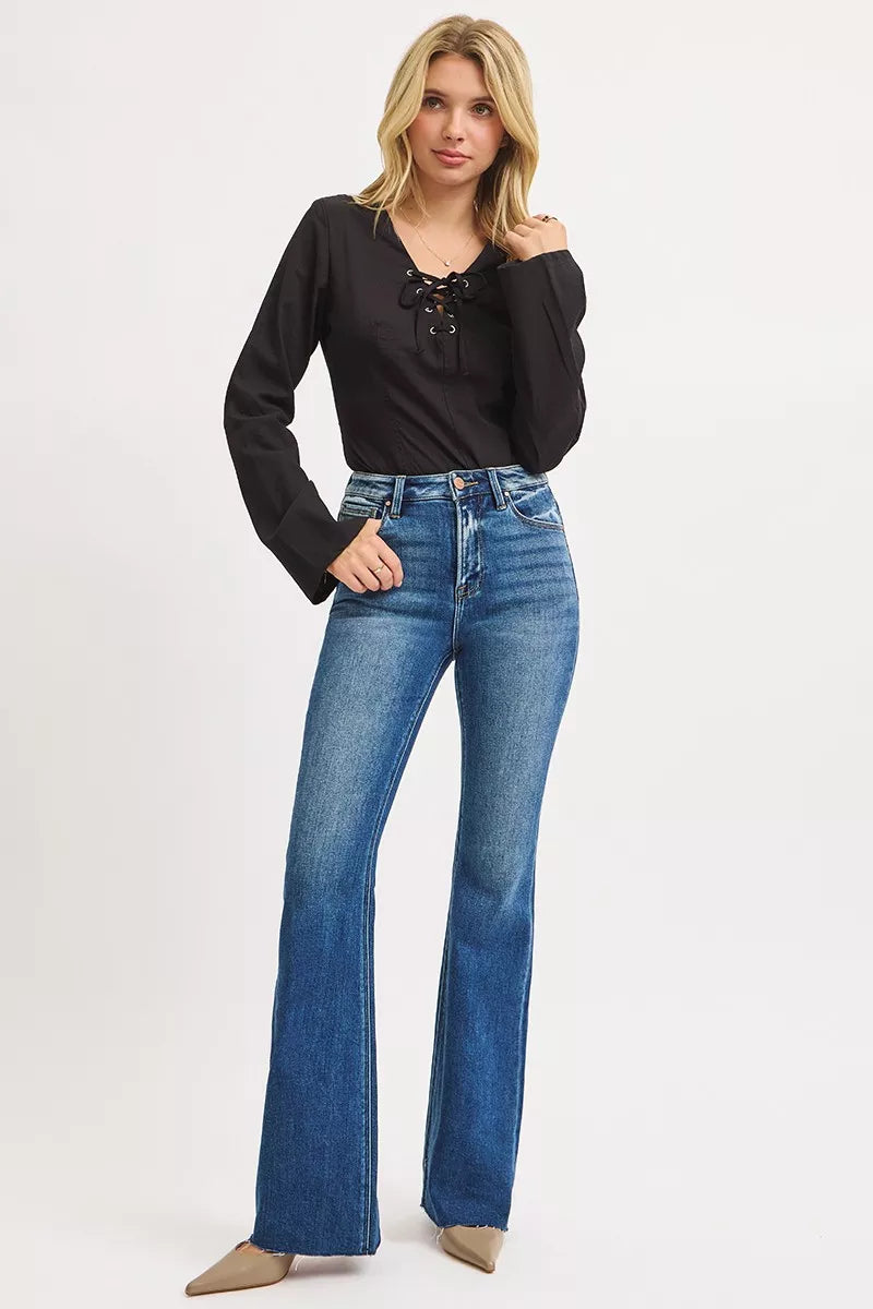 Woman wearing a black top and blue jeans on a white background