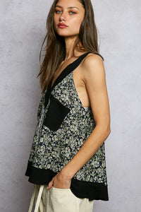 Woman wearing a floral sleeveless top with black accents against a gray background