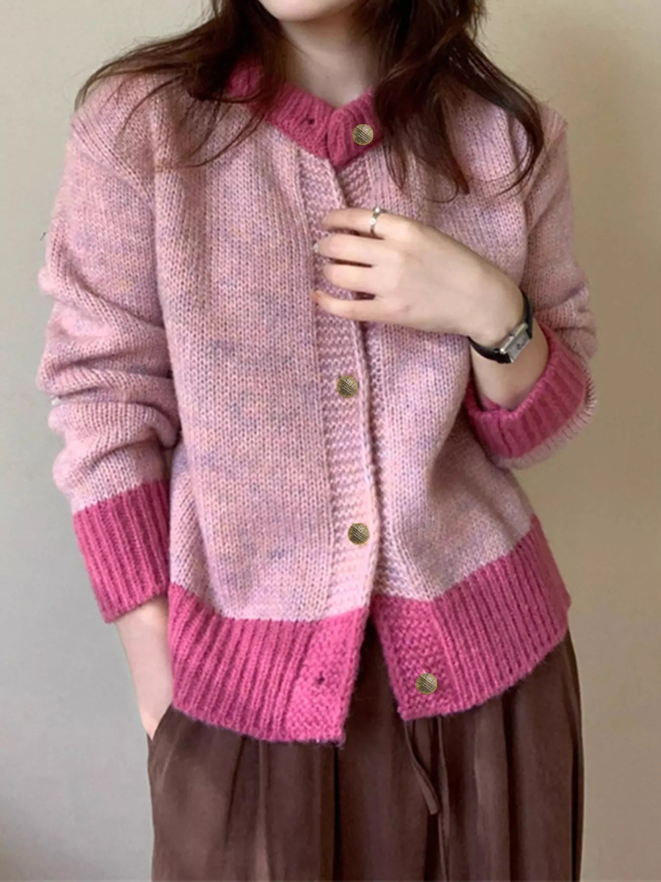 Person wearing a pink knitted cardigan with a plain background