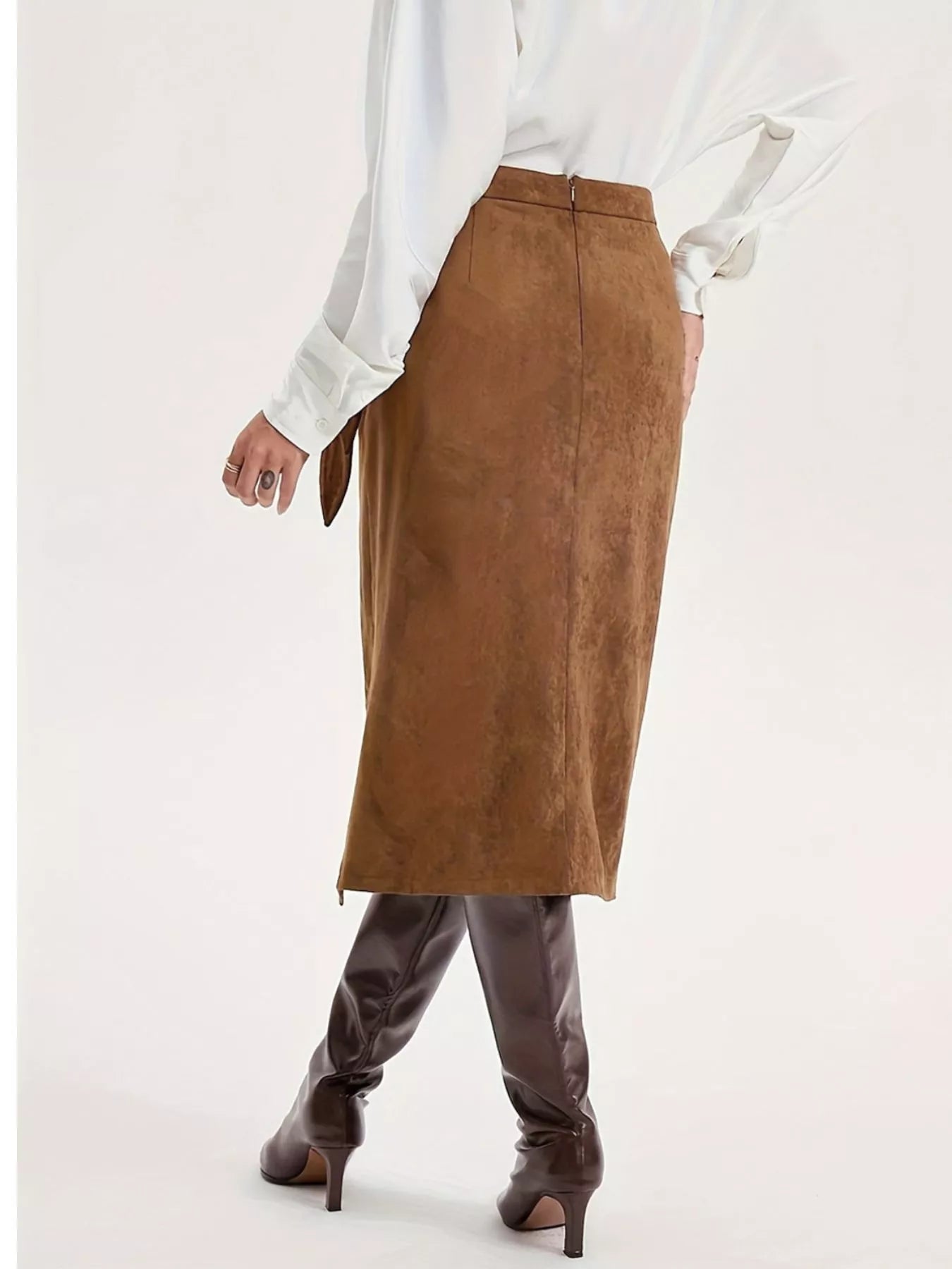 Person wearing a brown suede skirt with a white blouse on a white background