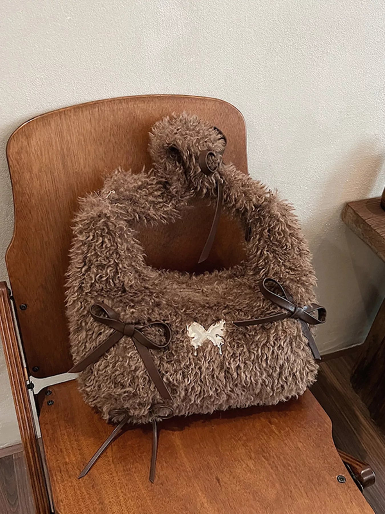 Brown fluffy pet carrier on a wooden chair against a white wall