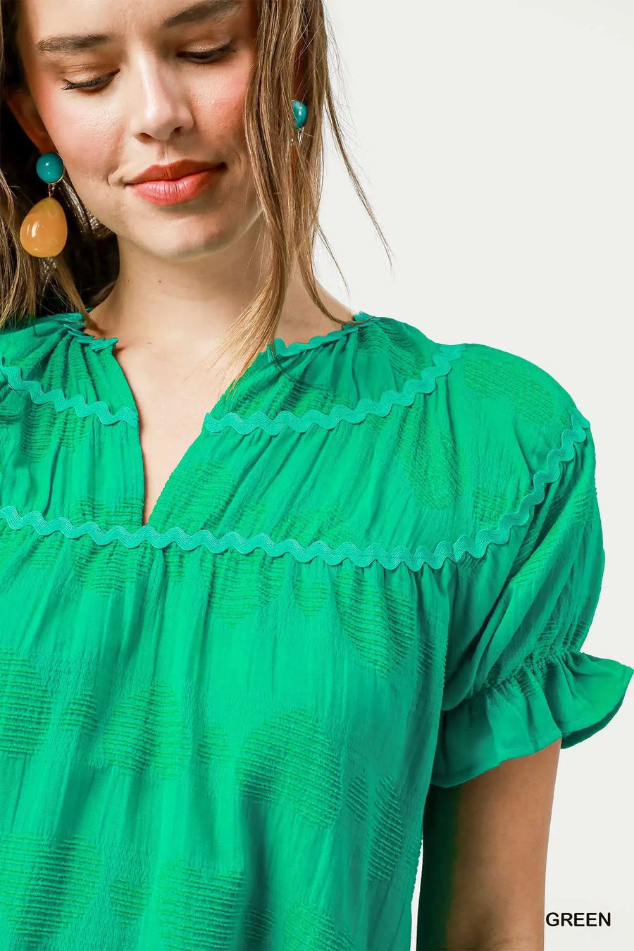 Woman wearing a green blouse with ruffled details on a white background
