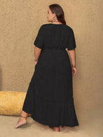 Woman wearing a black dress against a beige wall.
