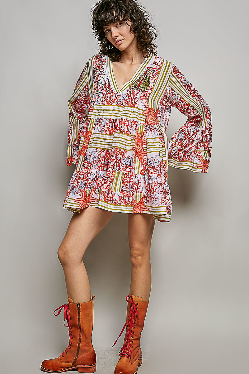 Woman wearing a colorful patterned dress with long sleeves and brown boots on a plain background