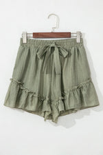Green ruffled shorts on a hanger against a white background