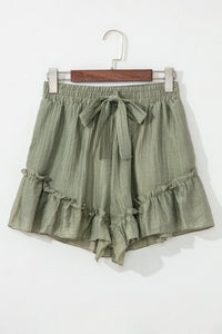 Green ruffled shorts on a hanger against a white background